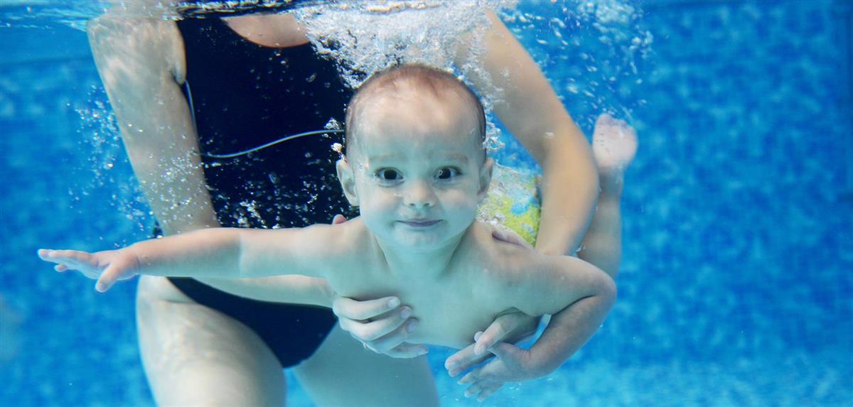 Ein vaksen i basseng som held en baby under vann - Klikk for stort bilete